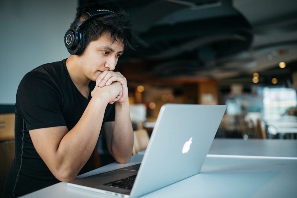 man-wearing-headphones-while-sitting-on-chair-in-front-of-macbook-4-eetnac1s4
