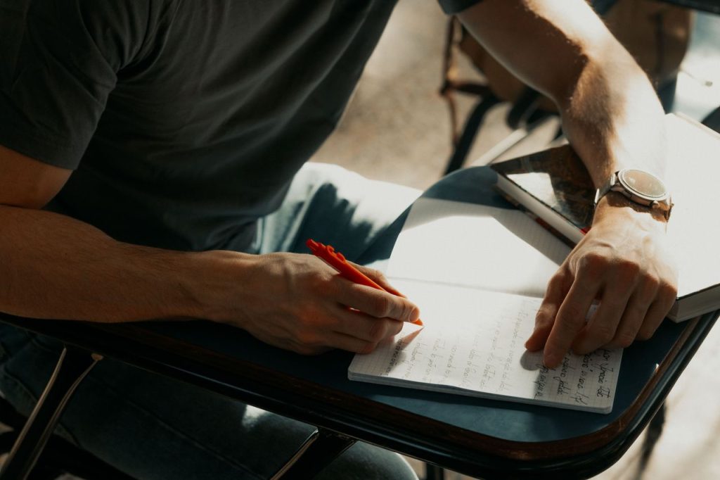 Focused student writing notes in a notebook during class.